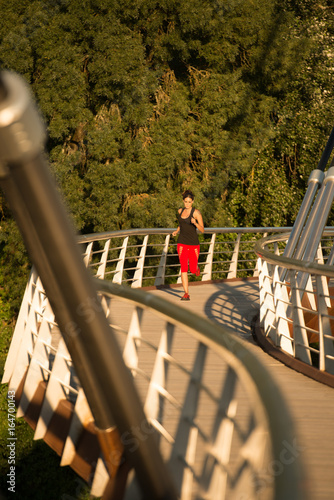 Beautiful woman running over bridge in the morning photo