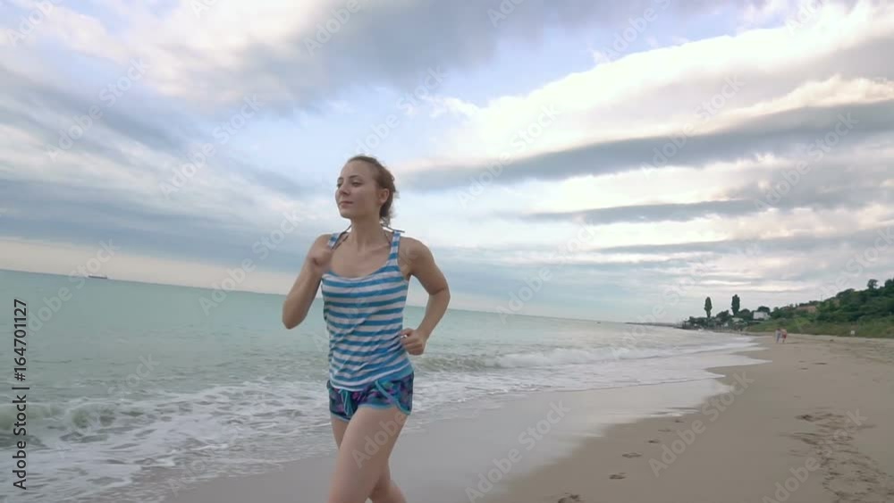 Athletic young woman running on the beach in slow motion Athletic young woman running on the beach in slow motion