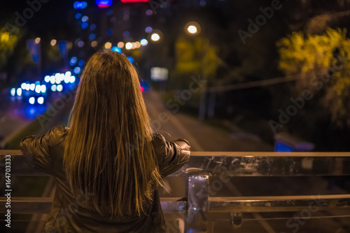 Young woman watching the view night city road from bridge photo