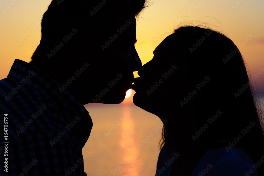 A loving couple kisses standing on the beach at sunset. Love and romance. He and she.