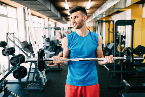 Young attractive man doing exercises in gym
