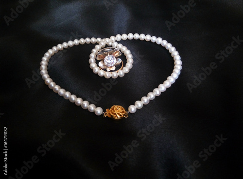 white pearl necklace with rings on black silky background