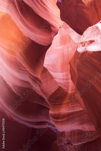 Nature red sandstone textured background. Swirls of old red sandstone wall abstract pattern and sun beam in the amazing Upper Antelope Canyon, Page, Arizona, USA.