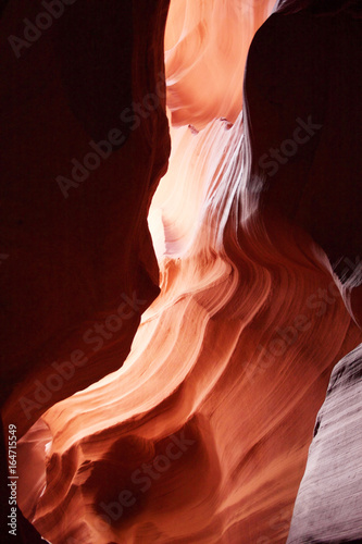 Nature red sandstone textured background. Swirls of old red sandstone wall abstract pattern and sun beam in the amazing Upper Antelope Canyon, Page, Arizona, USA.