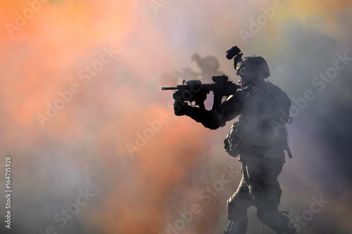 Soldier with rifle walking through colored smoke
