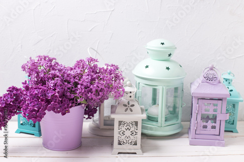Lilac flowers and brigh lanterns on white wooden background