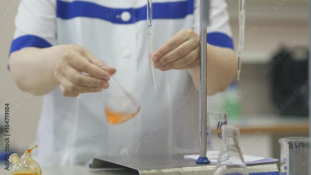 Lab assistant's hands in a white coat: doing Microbiology experiments. Chemist holds flasks and beakers in his hands, conducts research. Chemical plant and dishes for experiments.