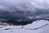 A landscape view from Hochtor tunnel on the Grossglockner high alpine road. Looking towards Heiligenblut in Carinthia with blue sky, mountains clouds and snow and the Grossglockner high alpine road.