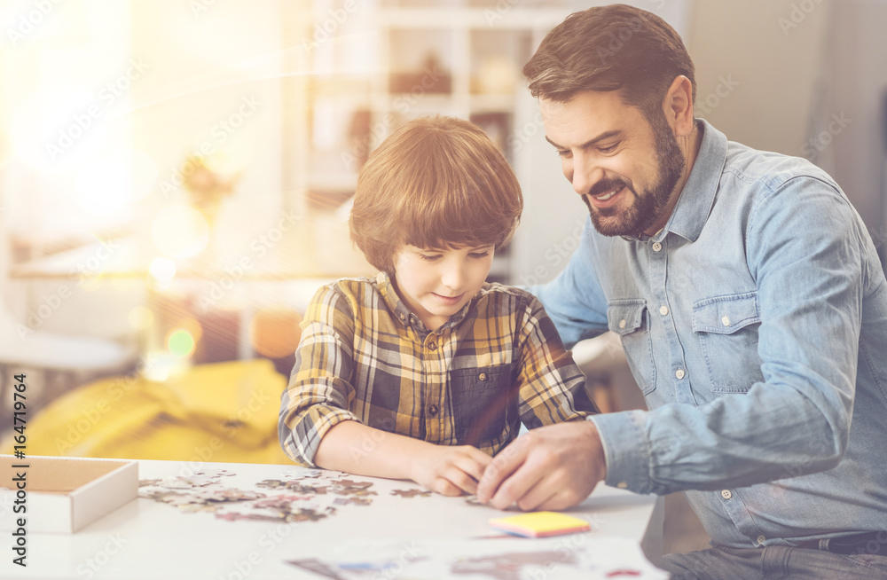 Nice intelligent boy doing a jigsaw puzzle with his father Nice intelligent boy doing a jigsaw puzzle with his father