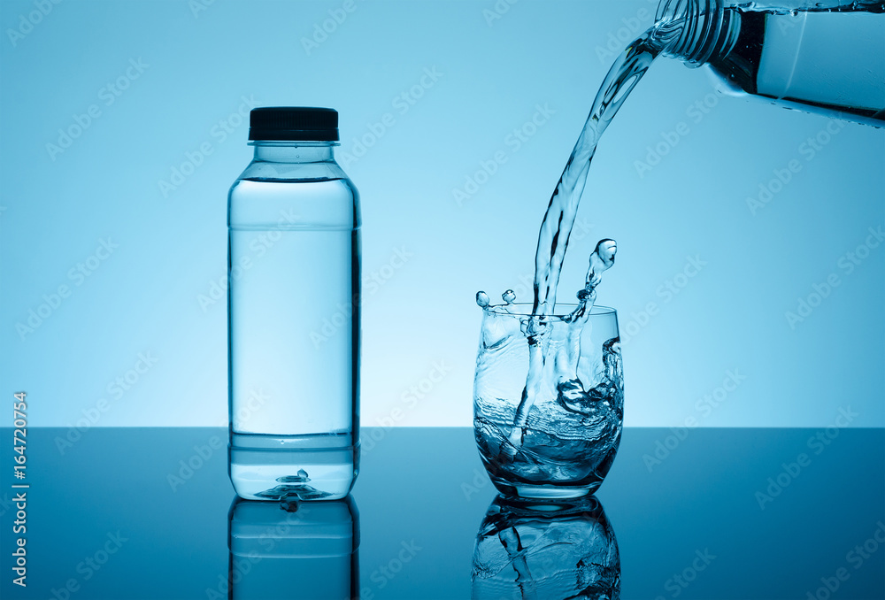 Bottle with creative splashing water in the glass Bottle with creative splashing water in the glass