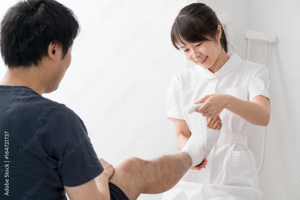 Obraz premium 足に包帯を巻く看護師、患者