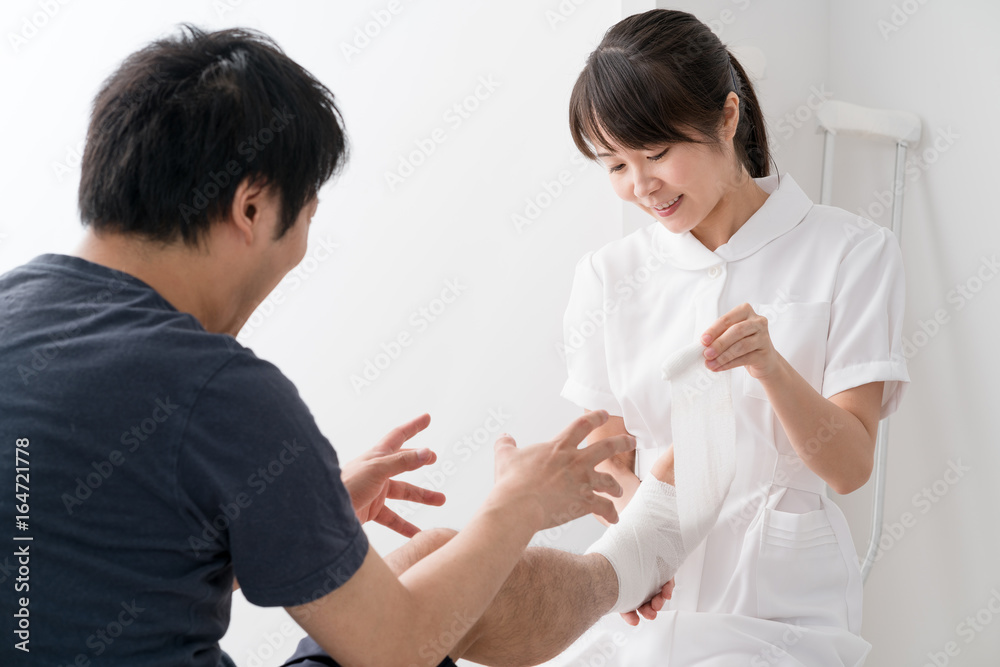 Fototapeta premium 足に包帯を巻く看護師、患者