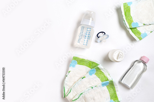 Fototapeta Naklejka Na Ścianę i Meble -  Babies goods diaper, baby powder, cream, shampoo, oil on white background with copy space. Top view or flat lay.