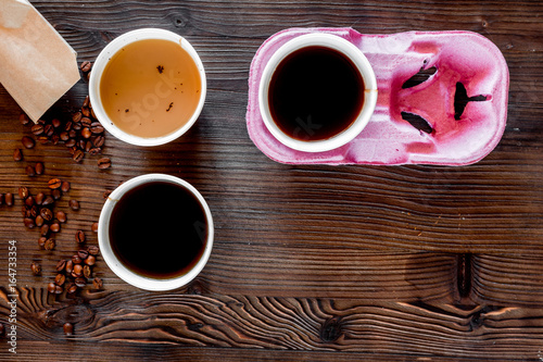 Coffee take away. Coffee cups with covers and coffee beans on wooden table backound top view copyspace photo