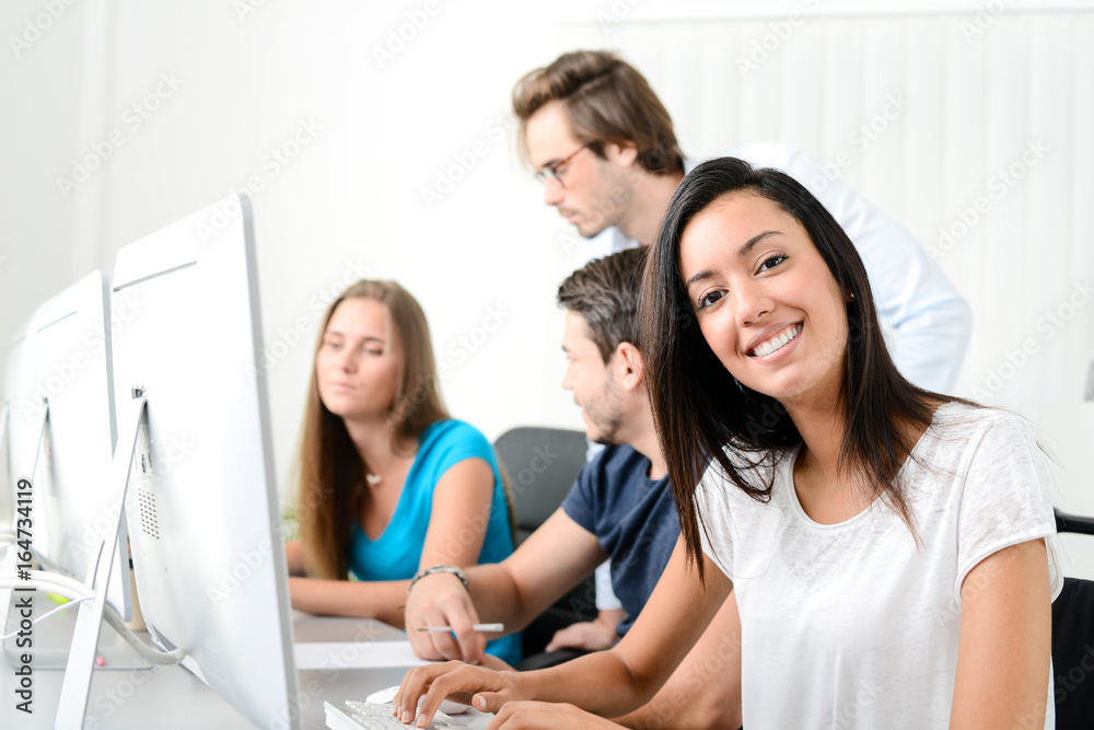portrait of young ethnic woman with people in business school office classroom working on desktop computer with teacher portrait of young ethnic woman with people in business school office classroom working on desktop computer with teacher