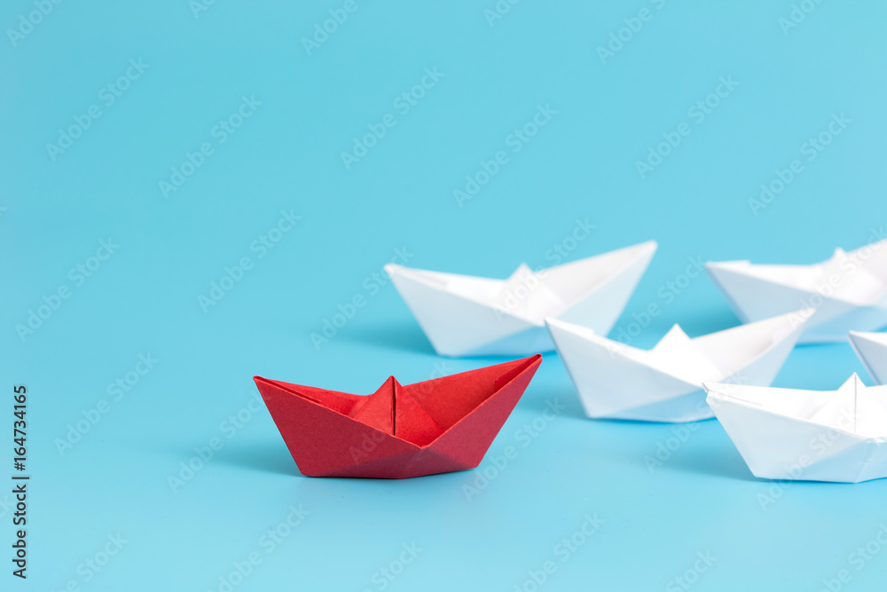 Leadership concept with red paper ship leading among white on blue background with copy space. Business leadership concept. Minimal style. Leadership concept with red paper ship leading among white on blue background with copy space. Business leadership concept. Minimal style.