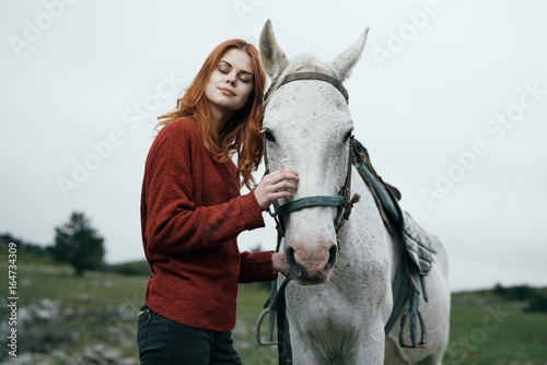 Young beautiful woman walks on nature in the mountains with horse