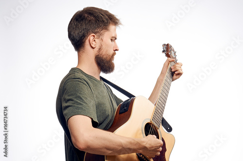 Young guy with a beard on a white isolated background holds a guitar