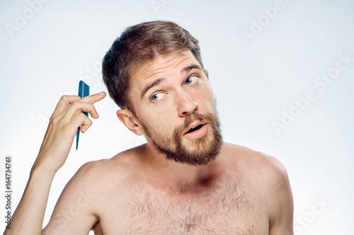Young guy with a beard on a white isolated background holds a comb