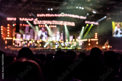 silhouettes of concert crowd in front of bright stage lights 