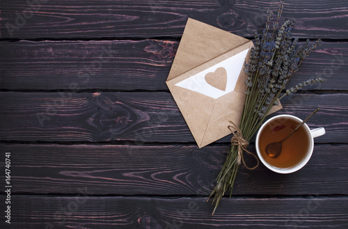 A cup of hot tea  lavender and a love letter on a dark wooden background top view. Herbal tea Hot drink Letter Lavender Love