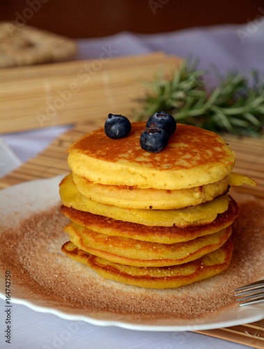 Stack of sweet homemade pancakes with fresh blueberries on a plate.