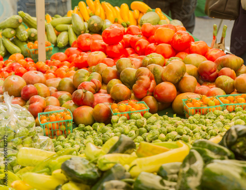 Farmer s market produce for sale at stand. Color horizontal photo of heirloom tomatoes  cherry tomatoes  brussel sprouts  zucchini  squashes  gypsy peppers and bell peppers are visible.