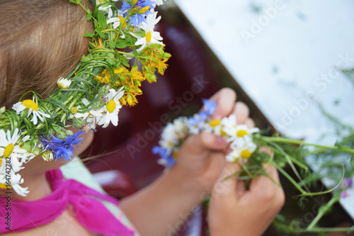 Hands clad in a garland of wild flowers to wear on the head