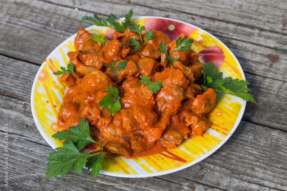 Chicken gizzard stew in plate on rustic wooden table Chicken gizzard stew in plate on rustic wooden table