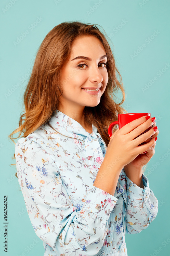 Portrait of young beautiful woman drinking coffee or tea over blue background Portrait of young beautiful woman drinking coffee or tea over blue background