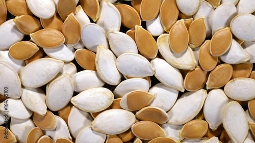 Excellent pumpkin seeds, white and brown, rotating clockwise. Flat lay of natural background with amazing texture in 4k, 3840x2160, clip. Eco product for healthy food.
