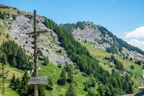 Crossroad sign with mountain peaks in the background in Grana Valley, Cuneo, Piedmont, Italy.
The readable text in the bottom sign (in Italian) means 