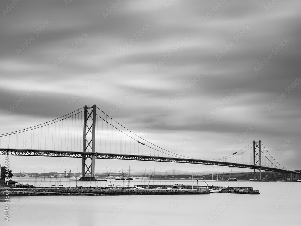 Long exposure b&w shot of the iconic Forth Road Bridge spanning over the Firth of Forth viewed from South-Queensferry. Scotland, UK
