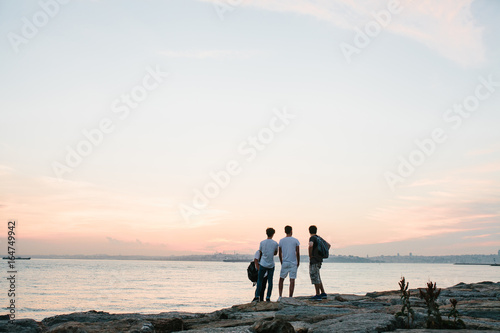 Friends stand on the coast next to the sea and communicate. Rest, friendship, holiday.
