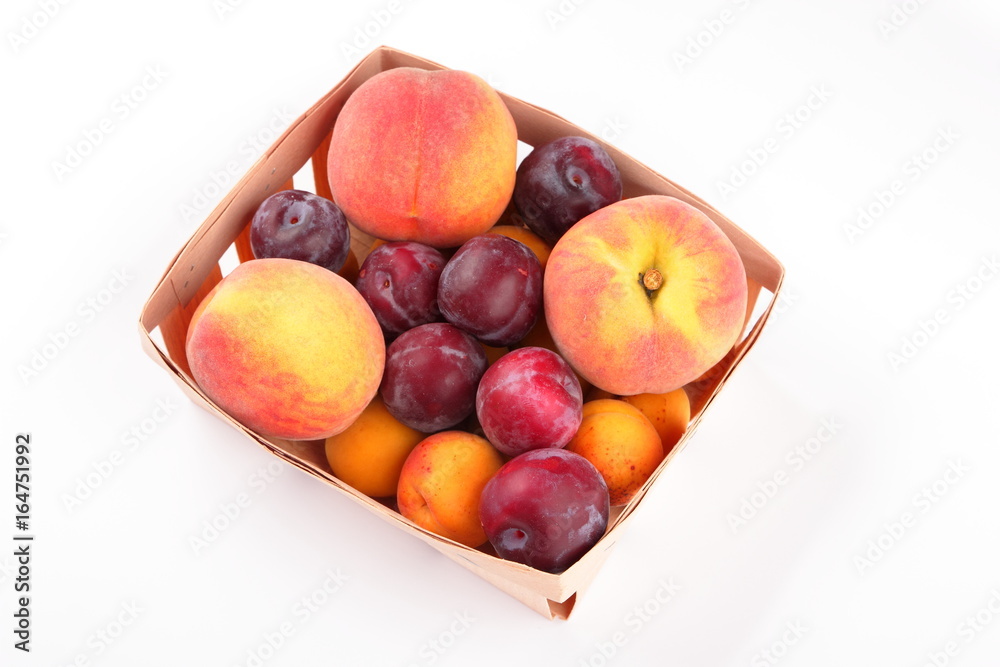 Peaches, apricots and plums in a basket isolated on white background Peaches, apricots and plums in a basket isolated on white background