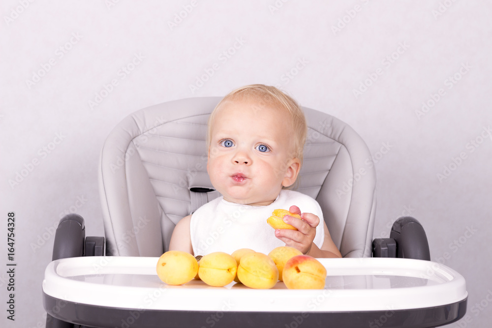 Funny toddler in a white bip eating an apricot Funny toddler in a white bip eating an apricot