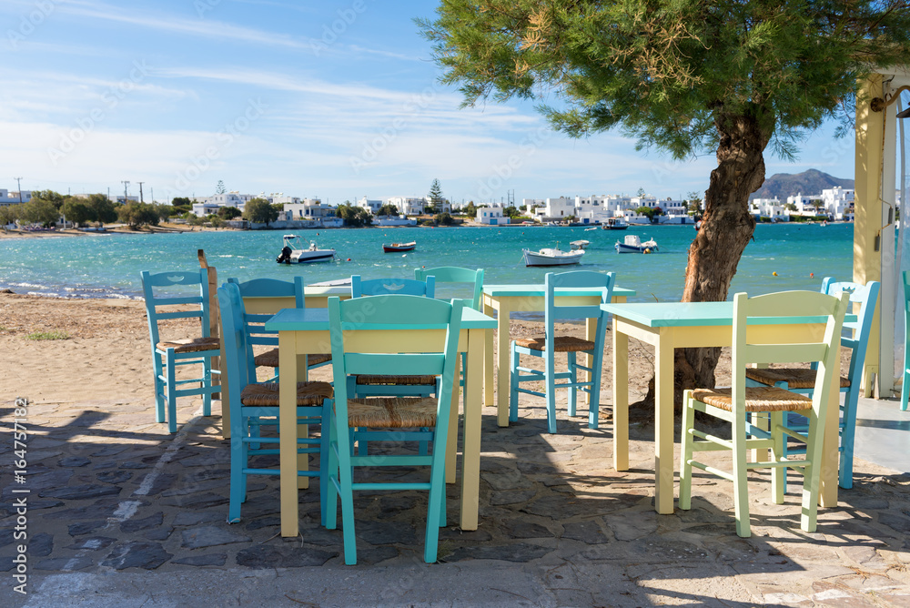 Colorful tables and chairs on coastal promenade in Pollonia village on Milos Island. Greece.