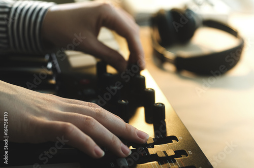 A woman in a shirt sets up a synthesizer, two hands in the frame