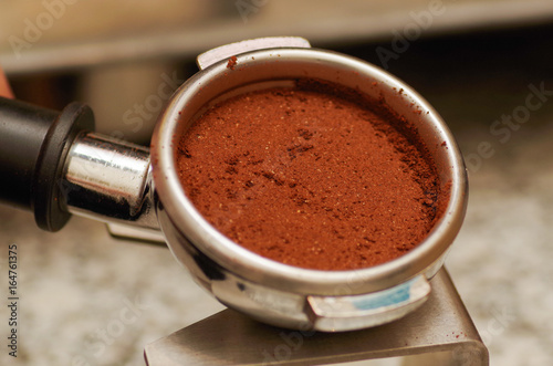 Close up of chocolate powder with cinnamon in a coffee strainer, in a blurred background