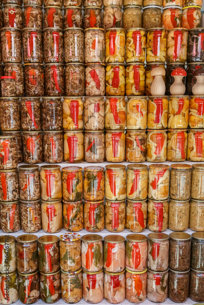 Handicraft canned jars with mushrooms, paprika  and other vegetables are stand on the shelf