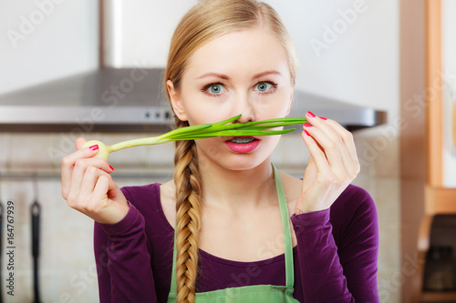 Woman in kitchen holds green fresh chive