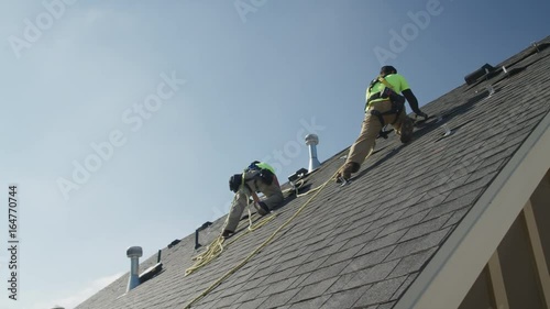 Wide panning low angle shot of workers installing parts on roof / Mapleton, Utah, United States photo