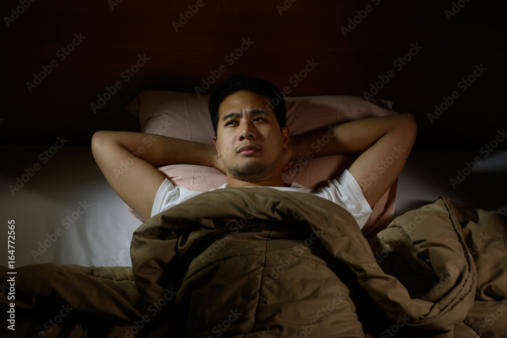 Depressed man suffering from insomnia lying in bed Depressed man suffering from insomnia lying in bed