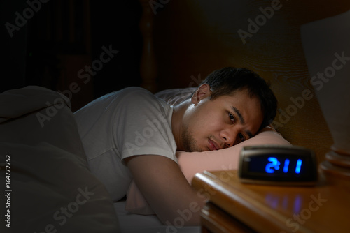 Depressed man suffering from insomnia lying in bed photo