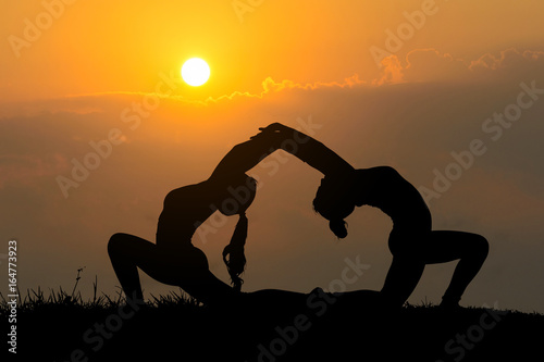 Silhouette young women practicing yoga at sunset