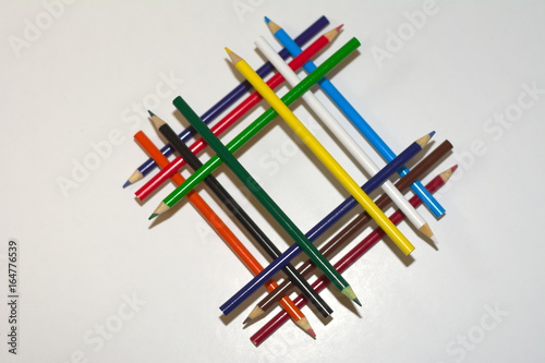 Different colored pencils stacked on top of ear other in a structural way portraying diversity and strength shot from a top angle on a white background photo