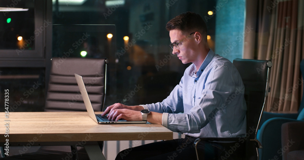 Fototapeta premium man working on laptop in dark office