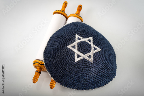 Judaism and jewish religious holiday concept with a closed Torah and a kippah also called a yamaka. Some of the better known jewish holidays are Tisha B'Av, Purim, Hannukah, Yom Kippur, etc