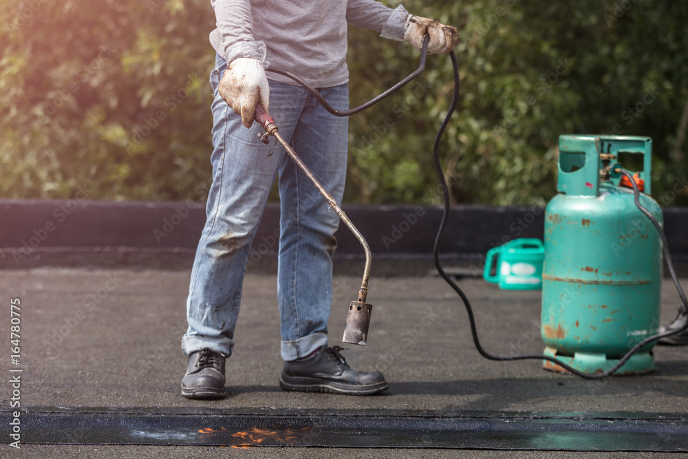 Group of worker installing tar foil on the rooftop of building. Waterproof system by gas and fire torching Group of worker installing tar foil on the rooftop of building. Waterproof system by gas and fire torching