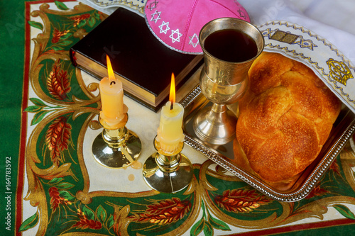 Shabbat candles in glass candlesticks with blurred covered challah background. photo